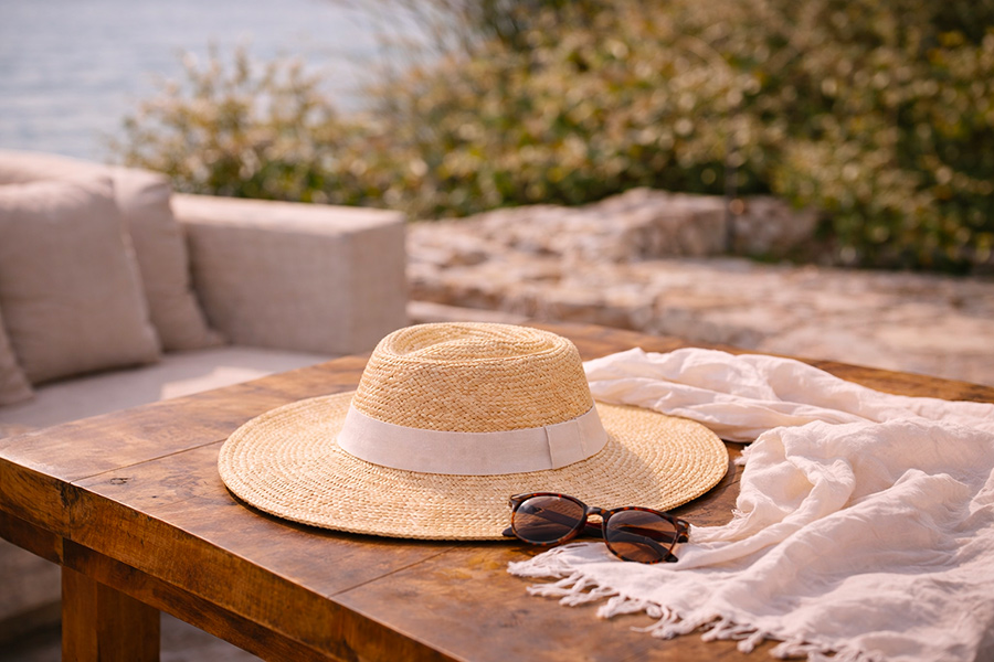 Capeline ronde posée avec lunettes de soleil dans une ambiance estivale chic